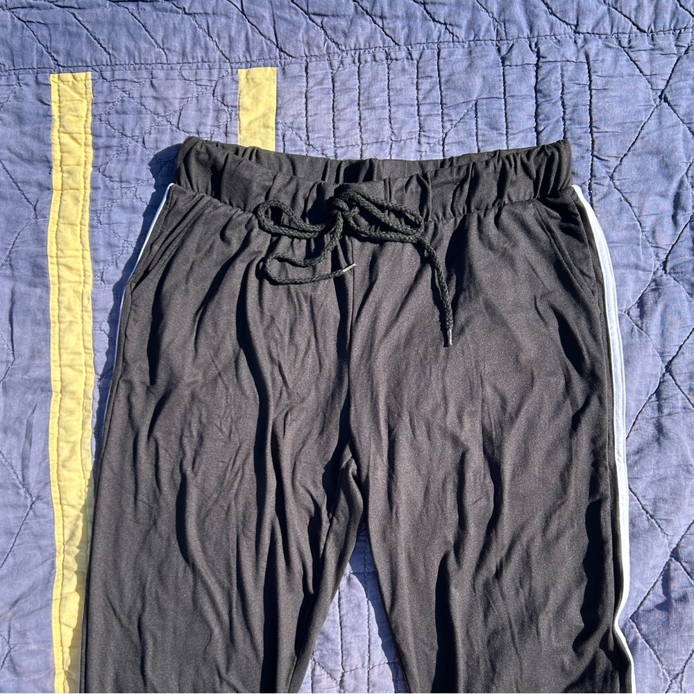 Black joggers with elastic waist, white stripes, drawstring, and elastic ankles